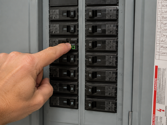 A finger switching off a circuit breaker in a residential electrical panel